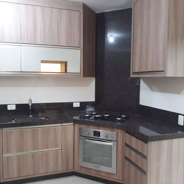 Cozinha em L com bancada em granito preto e forno embutido